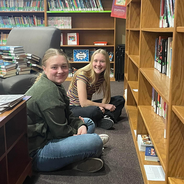 Two girls sitting on the floor of the library together