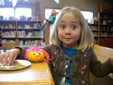 excited young girl eating stacks with a pink-haired pumpkin character